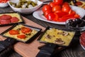 Young woman is preparing a traditional Swiss cheese raclette