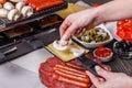 Young woman is preparing a traditional Swiss cheese raclette