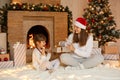Young woman presenting Christmas gift to her little daughter at Christmas morning, fun, happy time together, excited child being Royalty Free Stock Photo