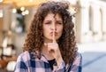 Young woman presses finger to lips makes silence hush sign do not tells gossip secret quiet in city Royalty Free Stock Photo
