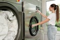 Young woman pressing buttons on washing machine