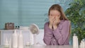 A young woman with problem skin covering her face with her hands, crying in frustration. A woman in pajamas sits at her Royalty Free Stock Photo