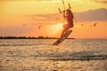 Young woman professional kiter performs a difficult trick in the air on a beautiful background of the sunset and sea Royalty Free Stock Photo