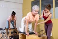 Young pilates instructor helping aged woman exercising on wunda chair Royalty Free Stock Photo