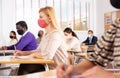 Woman in protective mask listening to lesson in extension school