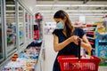 Young woman with protective face mask shopping for groceries in indoor groceries store.Coronavirus COVID-19 concept.Mandatory face