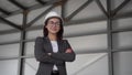 A young woman in a protective helmet and shows a thumb at a construction site. The boss in a suit looks at the camera.