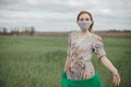 Young woman in protective mask in field. Lady quarantine in the village. Girl and quarantine . Covid-19. Europe Royalty Free Stock Photo