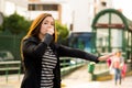 Young woman with protective mask overing her mouth with one hand and asking for a taxi with her other hand on the street Royalty Free Stock Photo