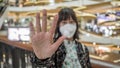 Young woman in protective sterile medical mask on her face, show hand, stop no sign. Air pollution, virus. coronavirus concept