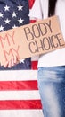 Young woman protester holds cardboard with My Body My Choice sign against USA flag on background. Girl protesting against anti- Royalty Free Stock Photo