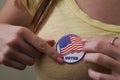 Woman applying an I voted sticker after voting