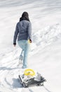 Young woman pulling a sledge in the deep snow, backview