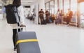 Young woman pulling suitcase in airport terminal. Young woman traveler in international airport with backpack holding suitcase or