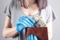 Young woman pulls money out of wallet with gloves