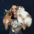 Young woman with a puppy and a cat in her arms