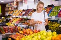 Young woman purchaser choosing apples in grocery