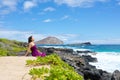 Young woman in purple dress sitting along rocky ocean shore Royalty Free Stock Photo