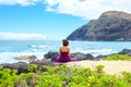 Young woman in purple dress sitting along rocky ocean shore Royalty Free Stock Photo