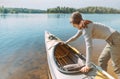 Young woman pushes a kayak in the water.