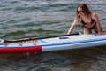 Young woman pushing a sup board in the sea. Healthy and fit life in the nature.