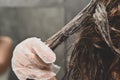 A young woman puts a healing mask on her hair at home