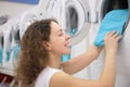 Young woman puts linen in washing machine in shop