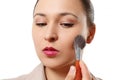 A young woman puts makeup on her face with a brush. on white background Royalty Free Stock Photo