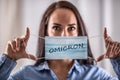 A young woman puts on a protective mask with the inscription Omicron Royalty Free Stock Photo