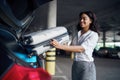 Young woman puts suitcases into the car on parking