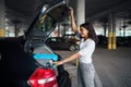 Young woman puts suitcases into the car on parking