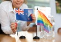 Young woman putting Australian and LGBT flags on table in office