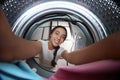 Young woman putting clothes into washing machine in bathroom, view from inside Royalty Free Stock Photo