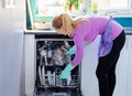 Young woman putting dirty dishes to dishwasher