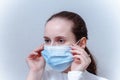 Young woman putting on face mask on a gray background Royalty Free Stock Photo