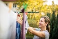 Young woman putting laundry on a rope in her garden Royalty Free Stock Photo