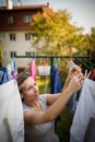 Young woman putting laundry on a rope in her garden Royalty Free Stock Photo