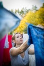 Young woman putting laundry on a rope in her garden Royalty Free Stock Photo