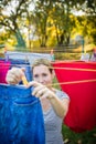 Young woman putting laundry on a rope in her garden Royalty Free Stock Photo