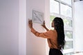 Woman Putting Photo Frame On Wall Royalty Free Stock Photo