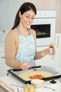 young woman putting pizza sauce on dough Royalty Free Stock Photo