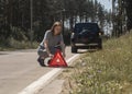 Young woman putting red triangle caution sign on road near broken car on roadside Royalty Free Stock Photo
