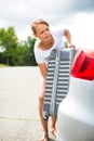Young woman putting a suitcase into her car's trunk Royalty Free Stock Photo