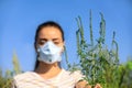 Young woman with ragweed branch suffering from allergy, focus on plant