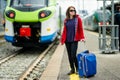 Young woman on a railway station. A girl waiting for a train on a platform. Female tourist with a luggage suitcase ready to travel Royalty Free Stock Photo