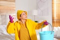 Young woman in raincoat collecting leaking water from ceiling at home. Time to call roof repair service Royalty Free Stock Photo