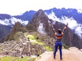 Young woman with raised arms on background of Machu Picchu.
