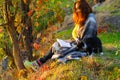 Young woman reading a book in the autumn park and petting a fluffy kitten. Royalty Free Stock Photo