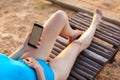 Young woman reading a book at the beach. A girl in a bathing suit lies on a deckchair and looks into the phone. Royalty Free Stock Photo