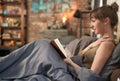 Woman reading book in bed at home